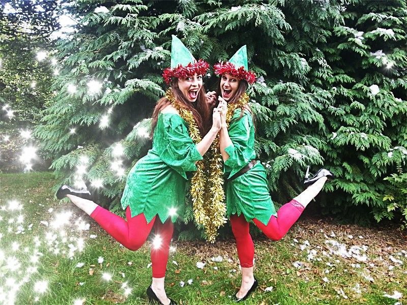 Dos animadoras caracterizadas de elfas con trajes verdes y gorros navideños